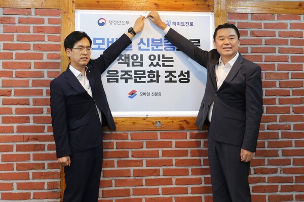 지난 14일 하이트진로 김인규 대표와 (오른쪽)김민재 행정안전부 차관이 행정안전부가 지정한 서울 서초동 하이트진로 본사 인근 착한가격업소를 방문해 모바일 신분증 활용을 권장하는 홍보 포스터를 부착했다. (사진=하이트진로)